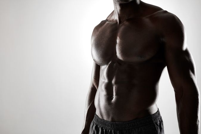 Close up shot of young man with muscular body against grey background