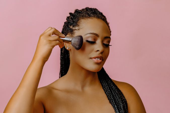 Black woman with make up brush to her cheek