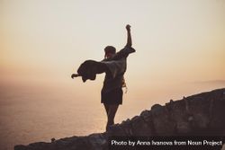 Woman with arms outstretched on castle wall overlooking sea, close up 5ak8Qb