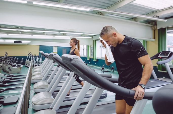 Man wiping brow after working out on treadmill