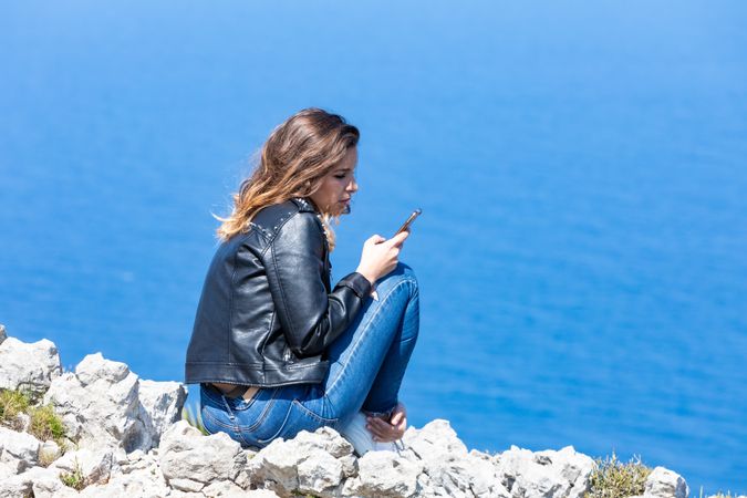 Young female using smartphone near sea