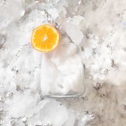 Orange slice resting on glass on sliver icy background