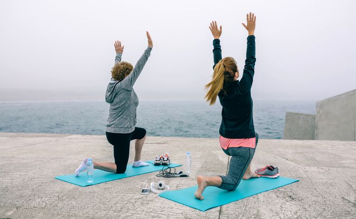 Back view of women stretching by sea pier