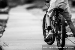 Back view of a boy riding bicycle on road in grayscale 0VJ2v0