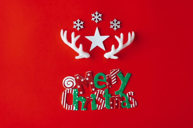 Reindeer antlers with star and snowflakes on red background with “Merry Christmas”