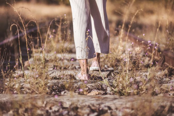 Long haired woman standing on railways overgrown with dry grass