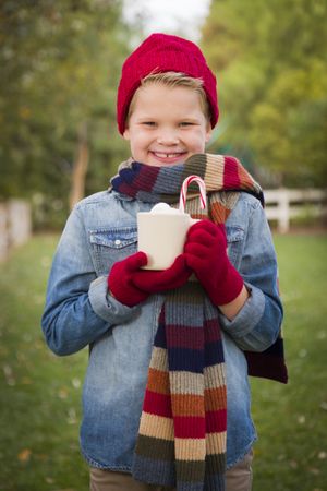 Young Boy in Warm Clothing Holding Hot Cocoa Mug Outside
