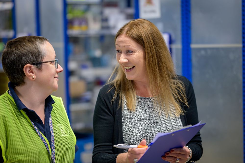 Two coworkers talking about stock in warehouse