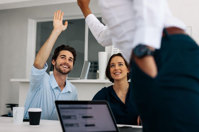 Business colleagues giving a high five sitting at the conference table