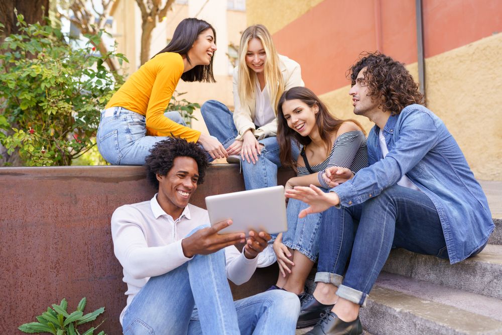 Multi-ethnic group gathered around a digital tablet outside