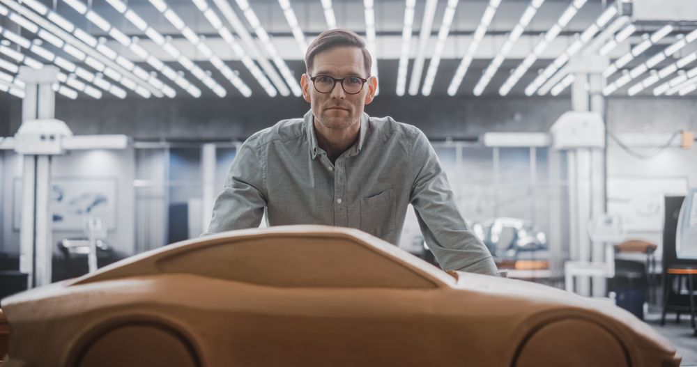 Portrait of an Automotive Designer in Glasses Working on a Prototype Car Out of Polymer Modeling Clay.