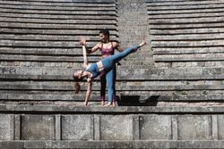 Instructor helping woman doing yoga in Half Moon pose