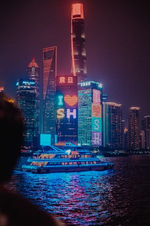 Boat on water near city buildings during night time