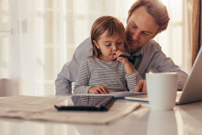 Father spending time with daughter while working at home
