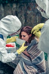 Doctors putting protective mask on woman infected with a virus