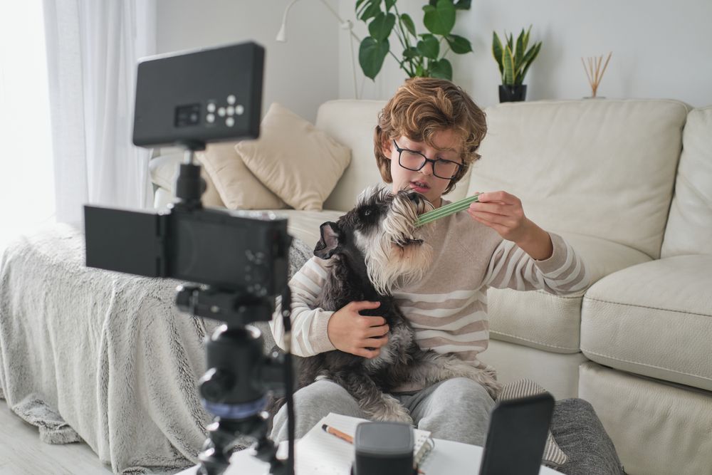 Preteen blogger recording video with dog at home
