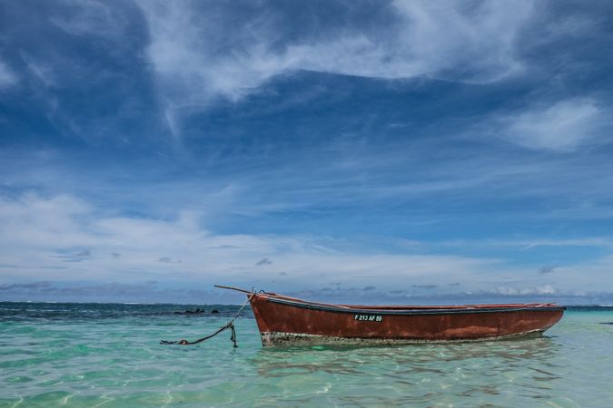 Red boat anchored in shallow tropical waters