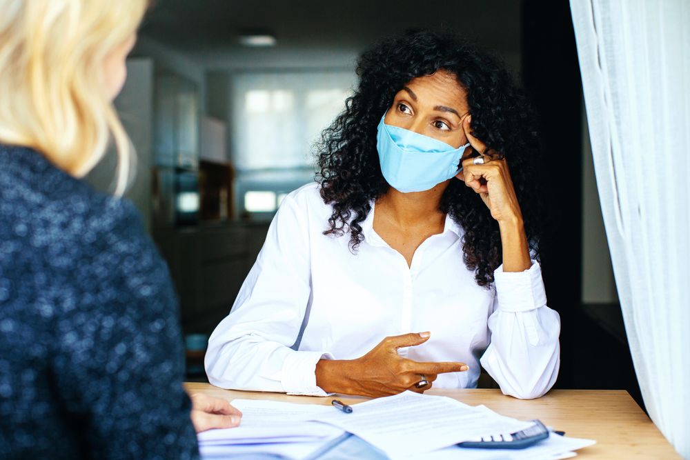 Two colleagues having a tense business discussion while wearing facemask