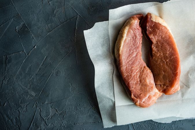 Top view of two raw pork chops on parchment paper