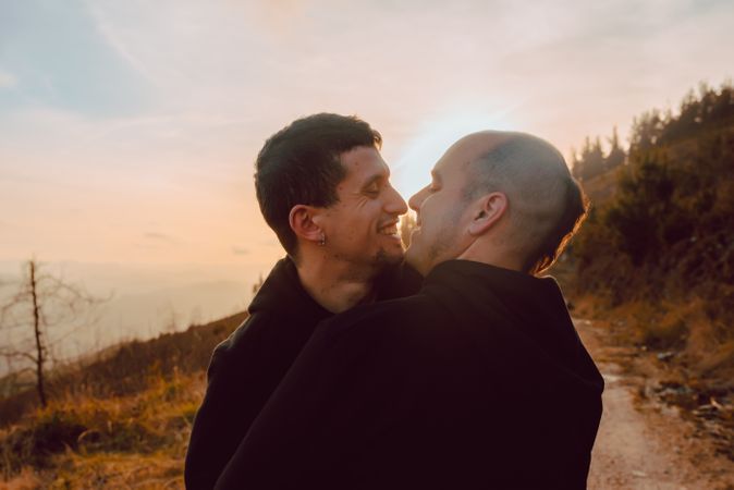 Men hugging and kissing in forest
