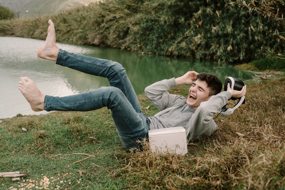 Young teenager with virtual reality glasses laughing outdoors