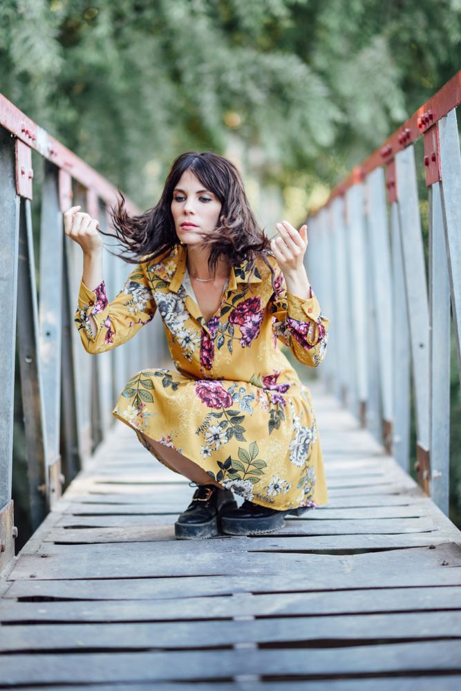 Female crouched down on a rural bridge