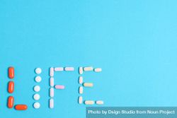 Multiple pills making the word "LIFE" with copy space 0yX8eL