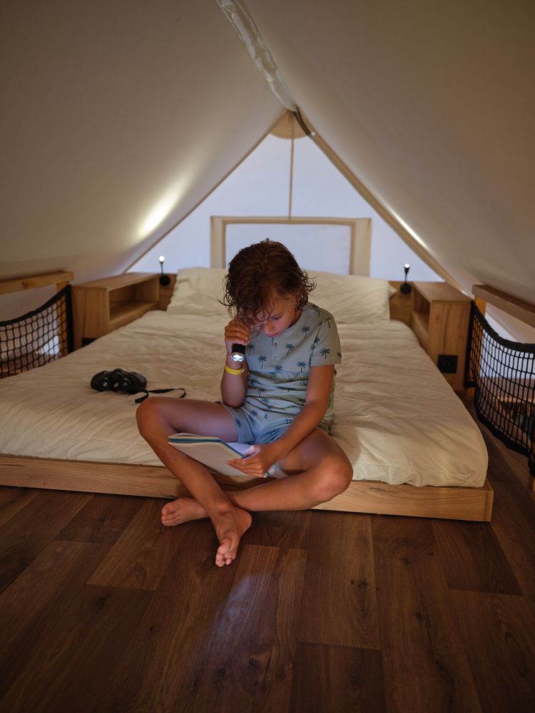 Focused boy reading notebook on bed