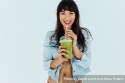 Portrait of beautiful woman drinking fresh green smoothie on light background bYPxN4