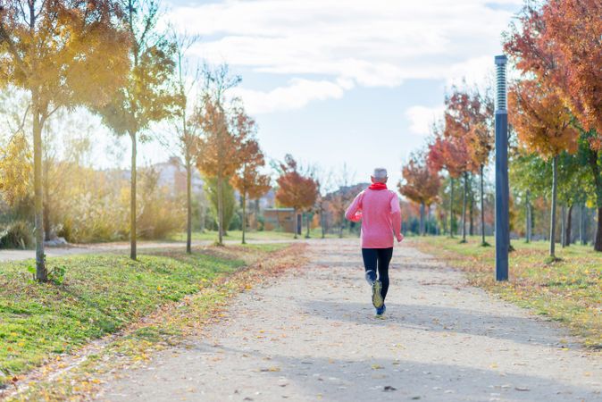 Back of male jogging in park with fall leaves