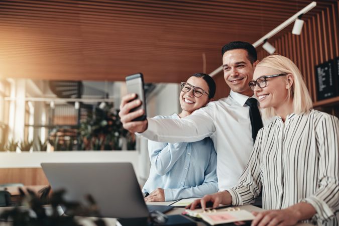 Group of professionals taking a selfie together in a bright modern office