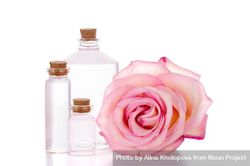 Three small glass bottles next to a rose bGrAA4