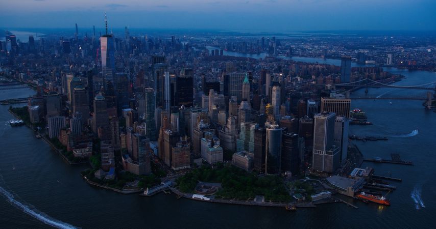 Evening Aerial View of Lower Manhattan Architecture. Panoramic Shot of Wall Street Financial District from a Helicopter. Office Buildings Next to Water Transportation in Hudson and East Rivers