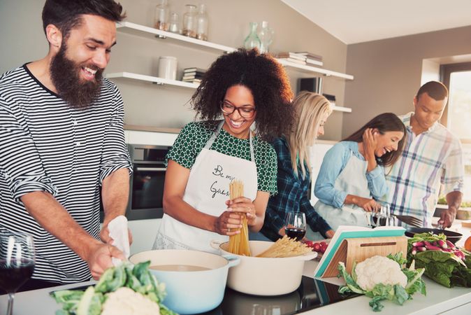 Five friends cooking at kitchen, having a lot of fun