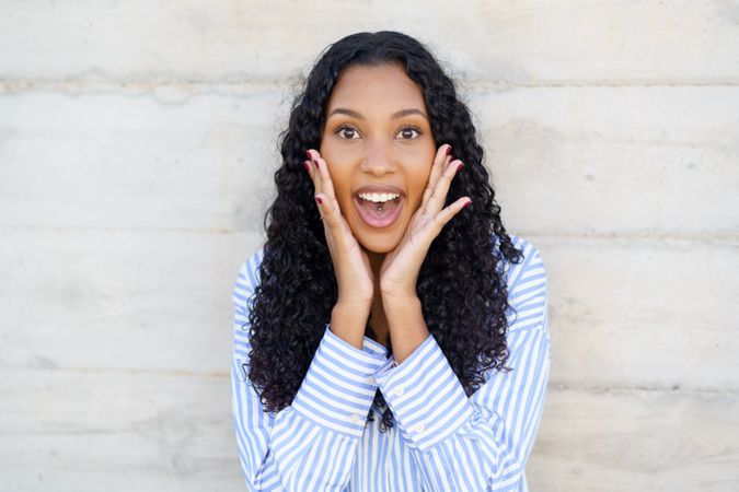 An Excited Young Woman with Beautiful Curly Hair Expressing Joy and Enthusiasm Clearly