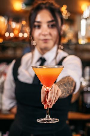 Young female bartender offering a drink