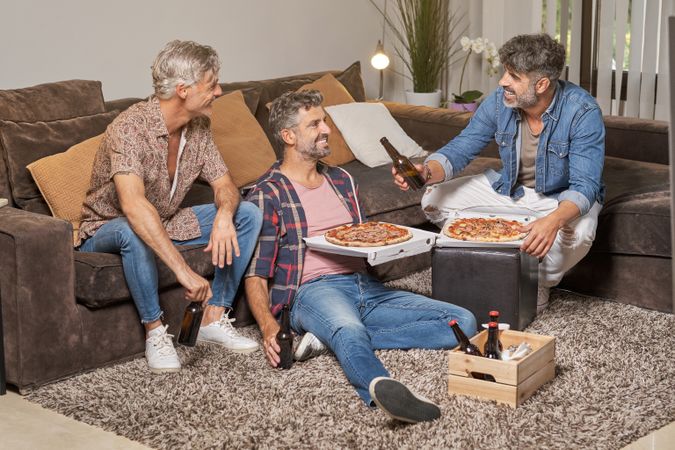 Happy friends having pizza and beer at home