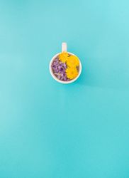 Mug with purple and yellow flowers in water with copy space