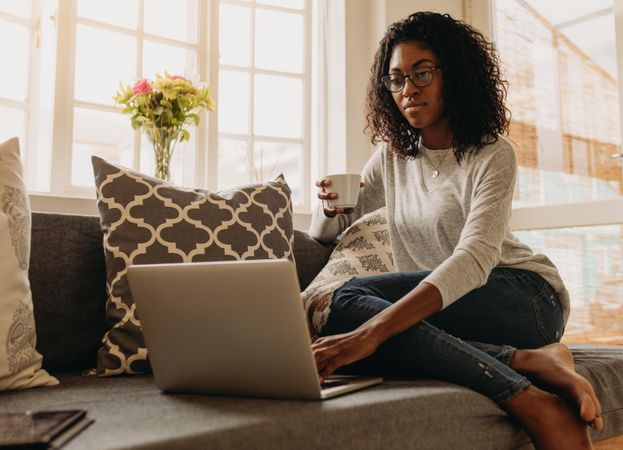 Woman sitting on sofa at home and managing her business
