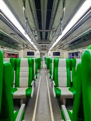 Modern train interior with comfortable seats and green color.