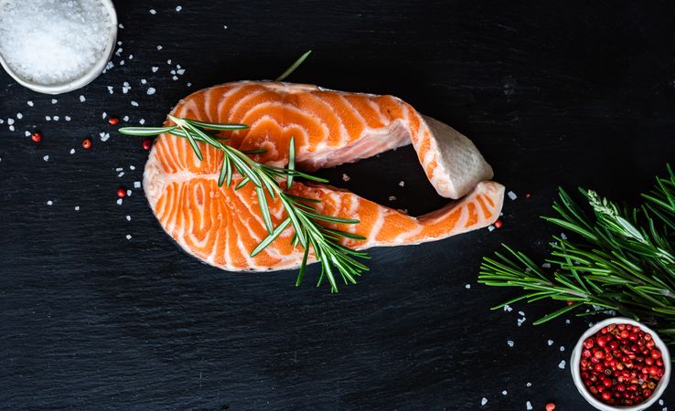 Fresh salmon steak with rosemary on dark counter with copy space