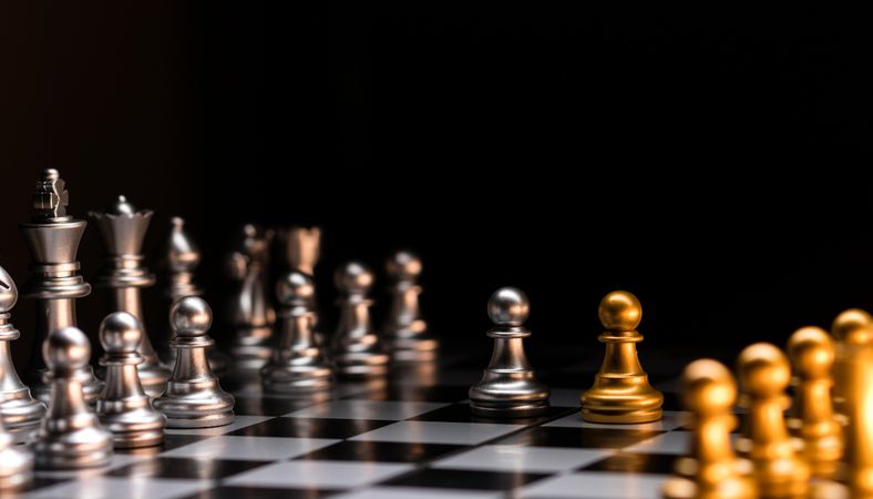 Chess standoff. Silver versus gold on chessboard.