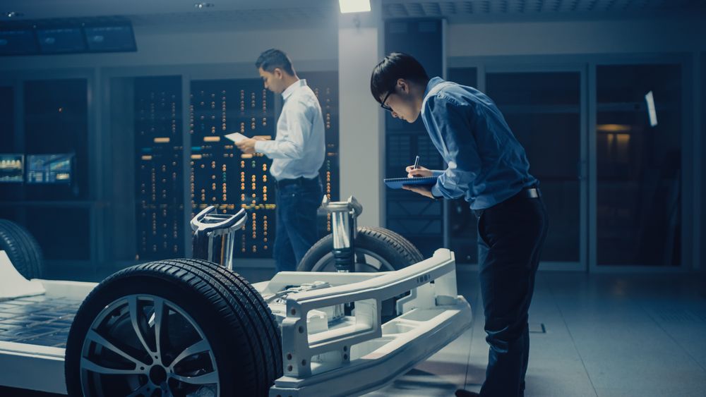 Automotive Engineers Working on Electric Car Chassis Platform, Taking Measurements