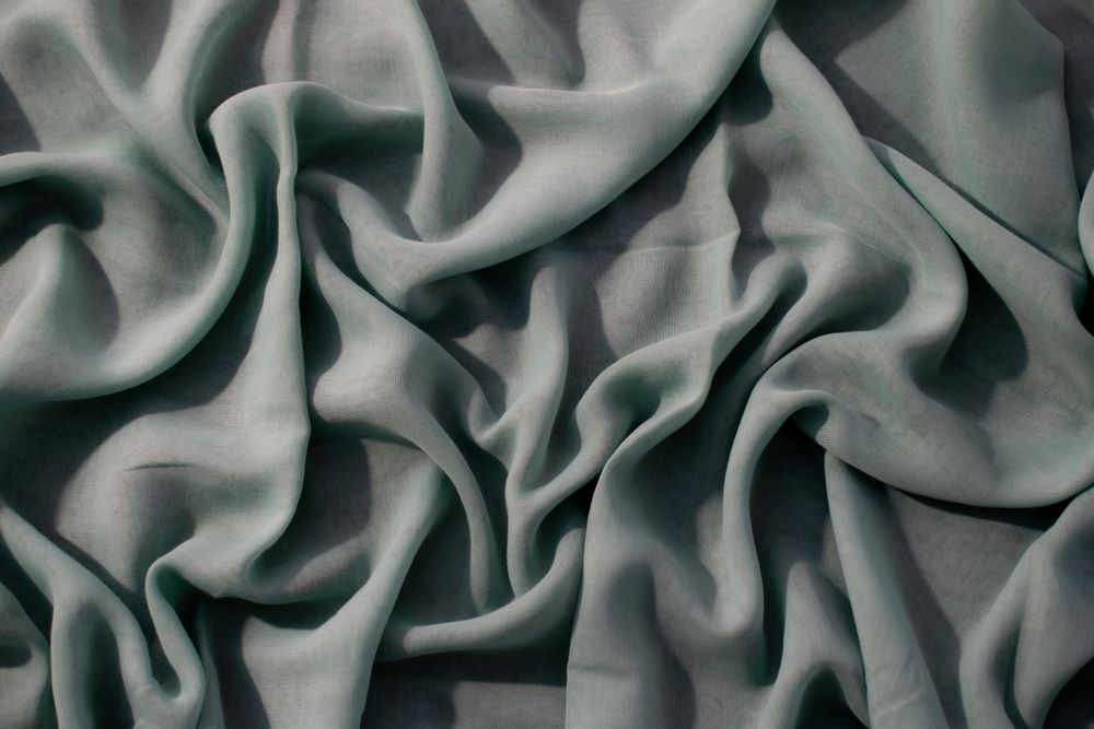 Nude green fabric wavy crumpled background texture with copy space.