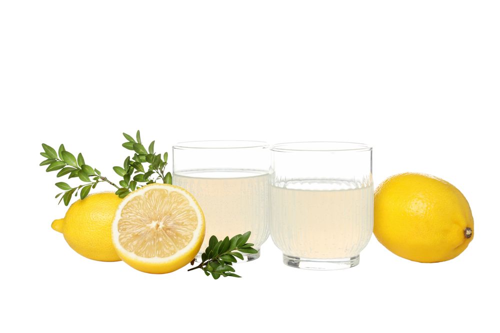 Lemons, branches and glasses with limoncello, isolated on light background