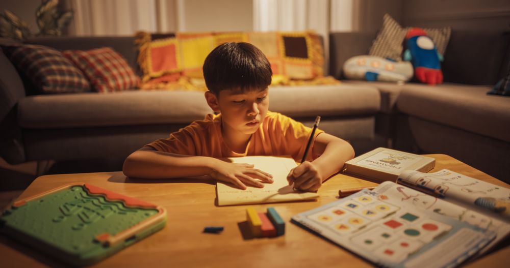 Portrait of a Cute Little Korean Boy Working on his Homework During Evening at Home.