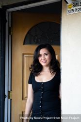 Woman standing in front of door at home smiling and looking at camera 4ZeXx5