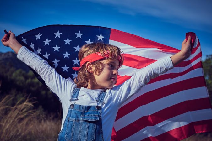 Positive preteen boy with USA waving flag over head