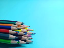 stack of colored pencils on blue background