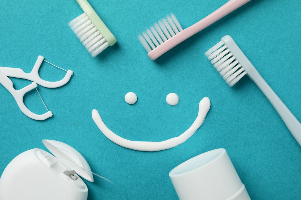 Smile and dental care tools on turquoise background, top view